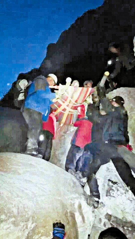 救援隊(duì)員用自制的簡(jiǎn)易擔(dān)架抬傷者。