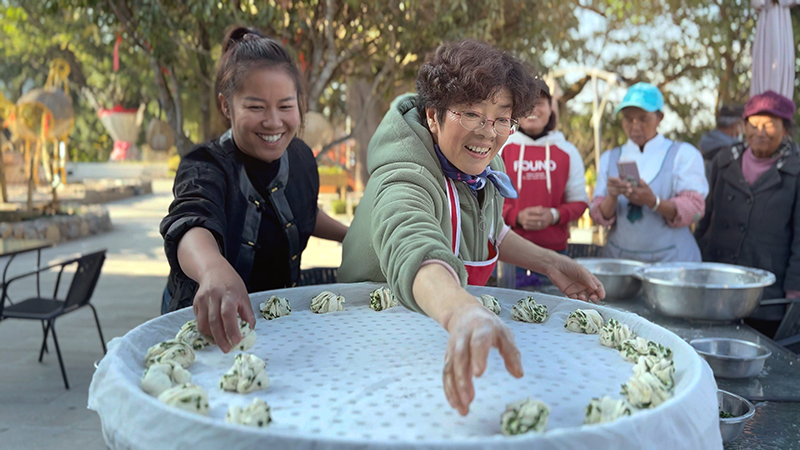 【2】旅居者趙發(fā)英（圖左二）教曼海村村民做花卷。陶思源-攝